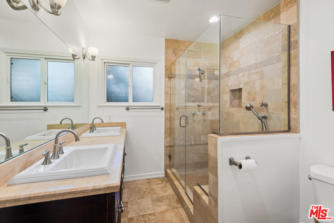 2621 Mandeville Canyon Road Los Angeles, CA 90049 - Photo 20 of 30 a bathroom with a sink a mirror a glass door a shower and vanity