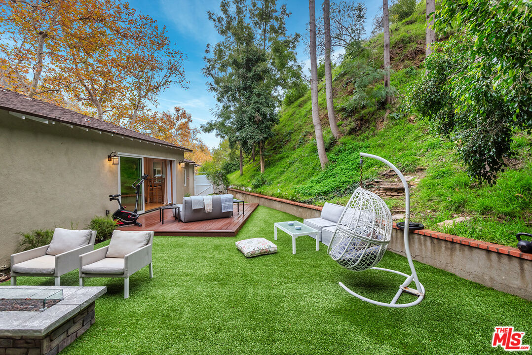 2621 Mandeville Canyon Road Los Angeles, CA 90049 - Photo 23 of 30 a view of a backyard with table and chairs a fire pit and plants