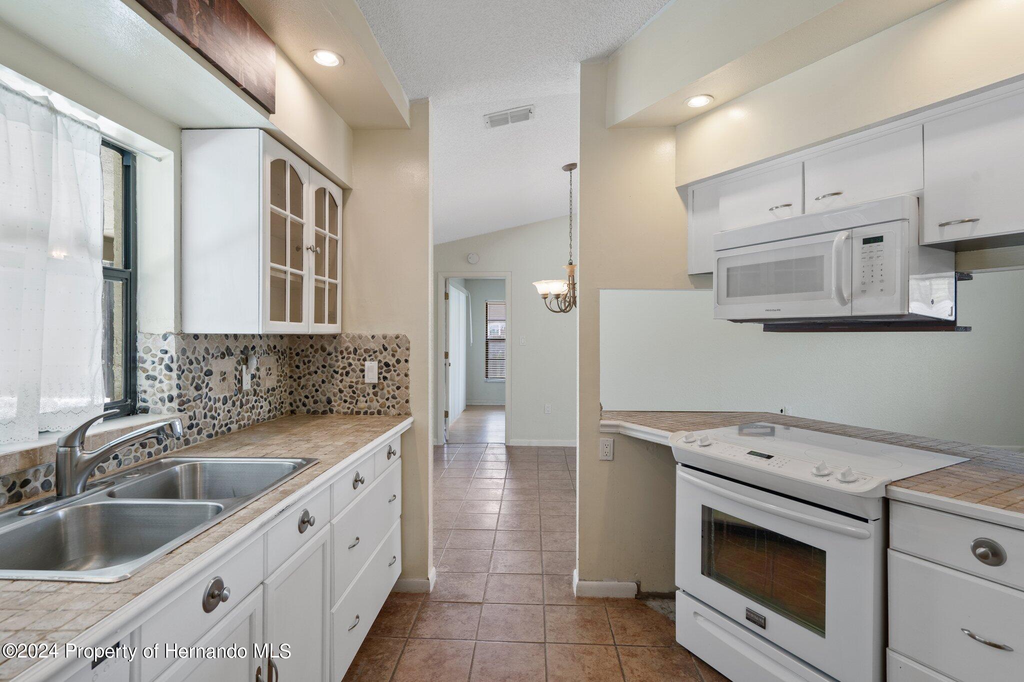 9290 Eldridge Road Spring Hill, FL 34608 - Photo 16 of 55 a kitchen with stainless steel appliances granite countertop a sink and cabinets