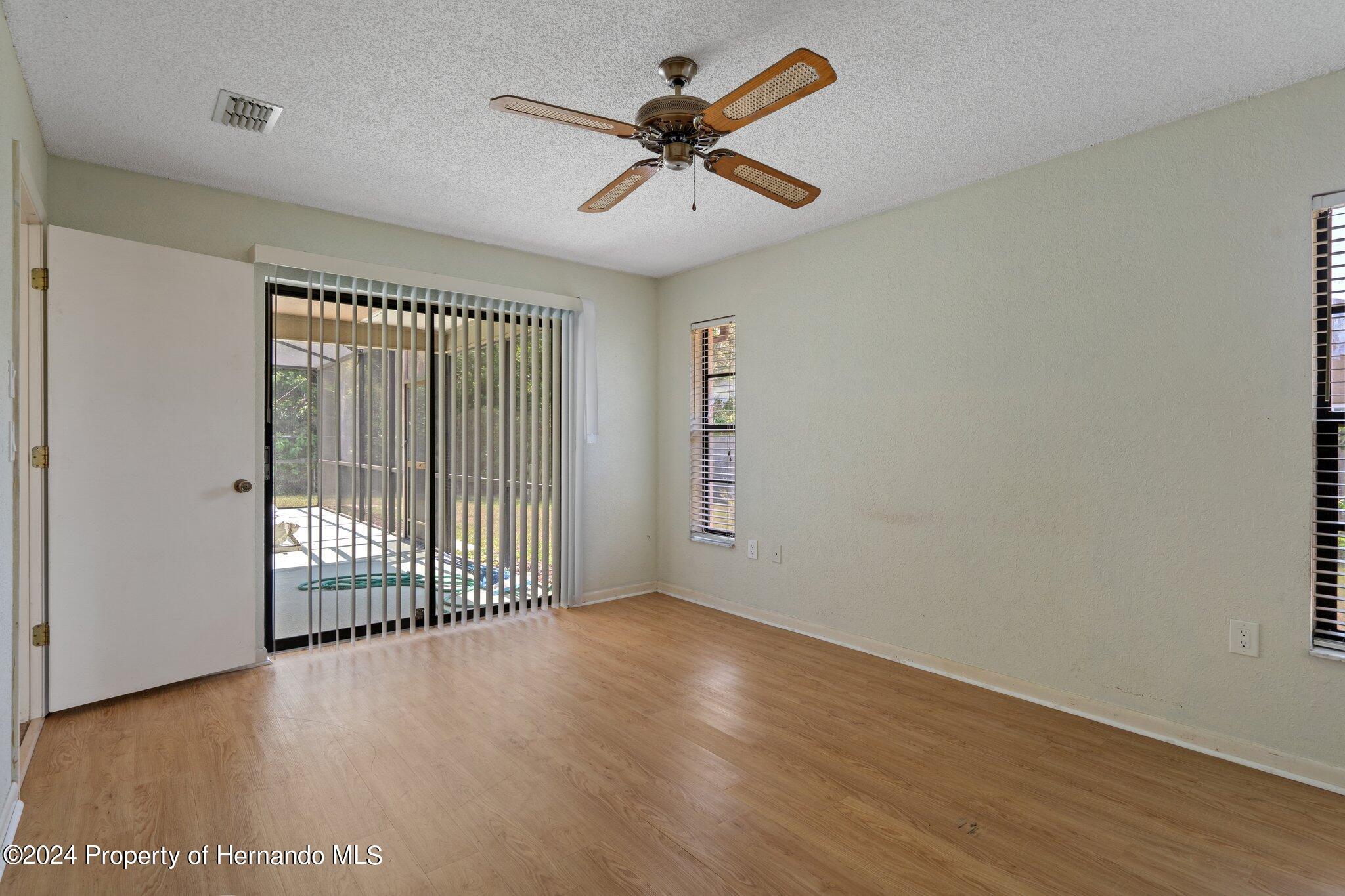 9290 Eldridge Road Spring Hill, FL 34608 - Photo 20 of 55 an empty room with wooden floor and windows
