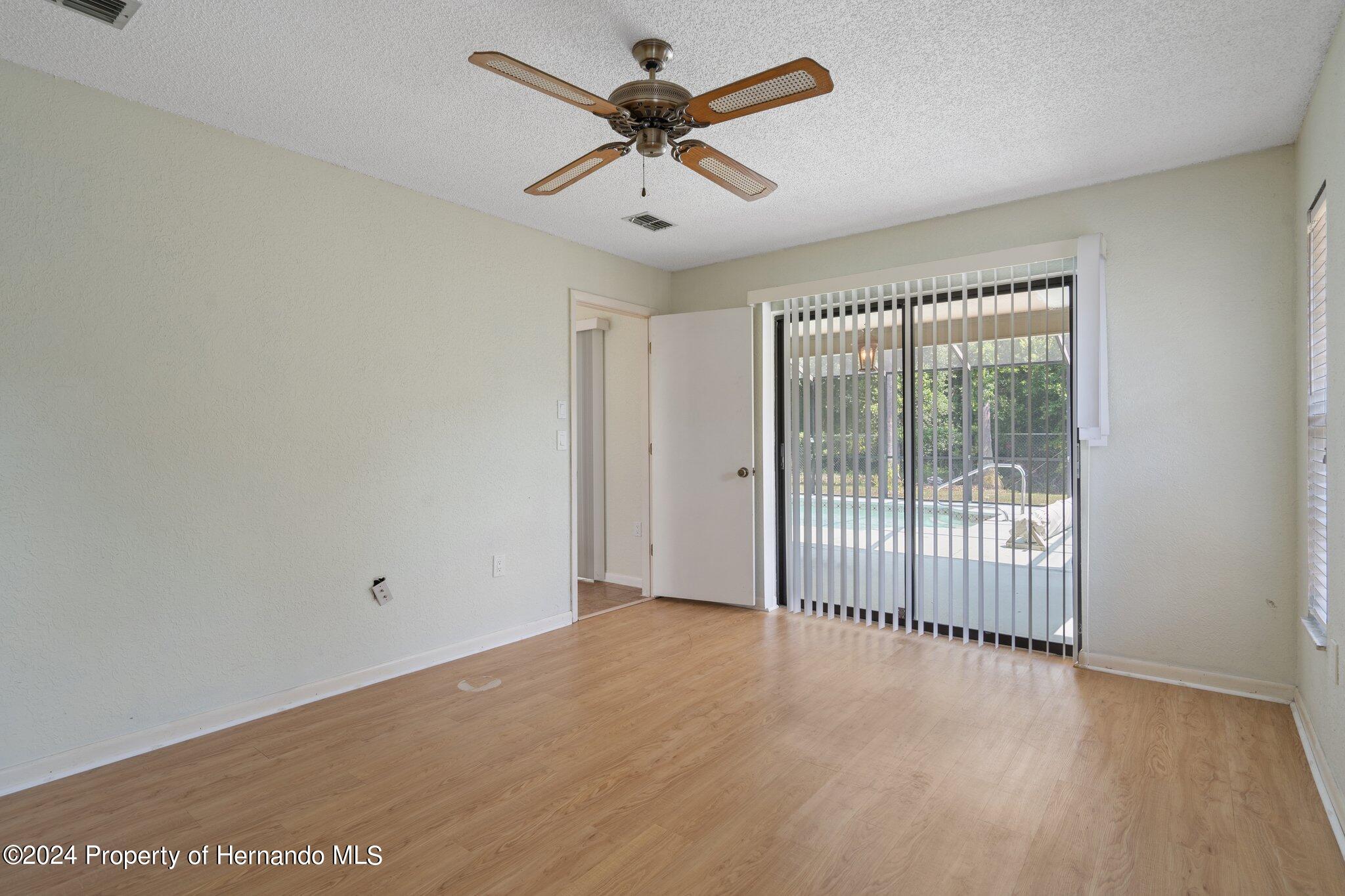 9290 Eldridge Road Spring Hill, FL 34608 - Photo 21 of 55 a view of a room with wooden floor and a ceiling fan