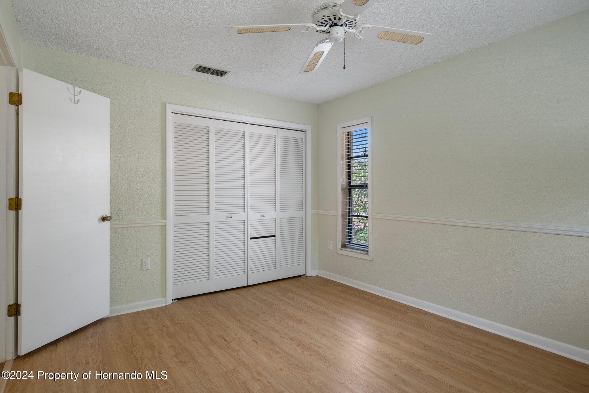 9290 Eldridge Road Spring Hill, FL 34608 - Photo 42 of 55 a view of empty room with wooden floor and fan