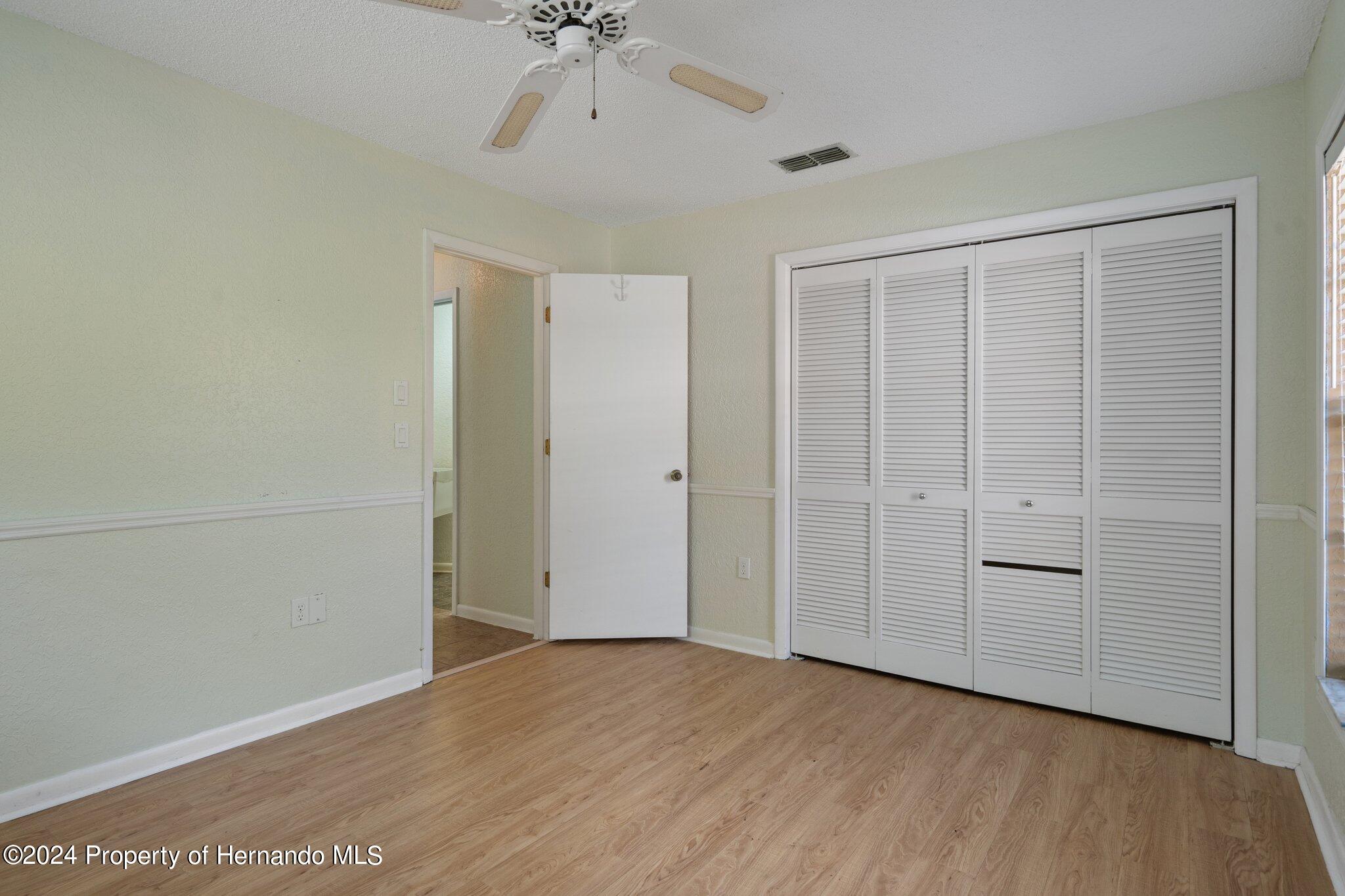 9290 Eldridge Road Spring Hill, FL 34608 - Photo 43 of 55 an empty room with a chandelier fan and wooden floor