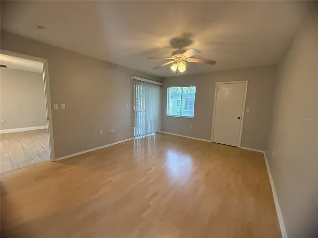 an empty room with windows and chandelier fan