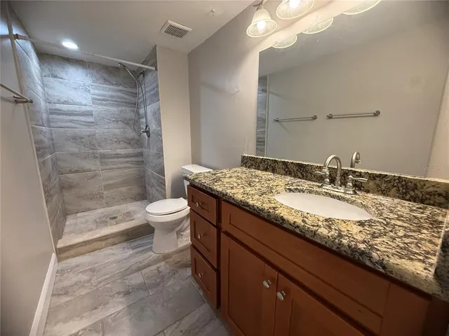 a bathroom with a granite countertop sink a toilet and shower
