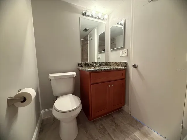 a bathroom with a granite countertop toilet sink and mirror