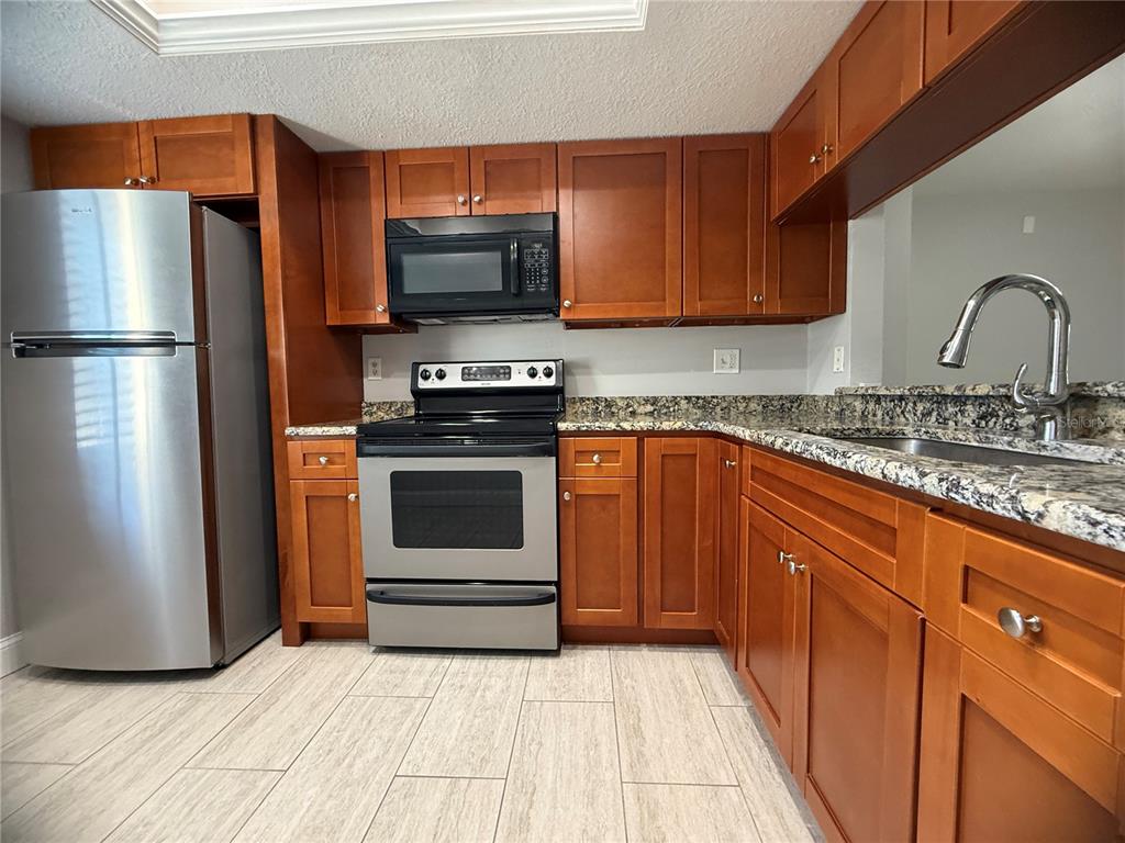 208 Palmetto Court, Unit 208 Oldsmar, FL 34677 - Photo 7 of 48 a kitchen with stainless steel appliances granite countertop a stove a sink and a refrigerator