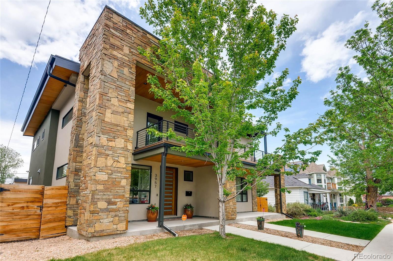a view of a brick house with a big yard plants and large trees