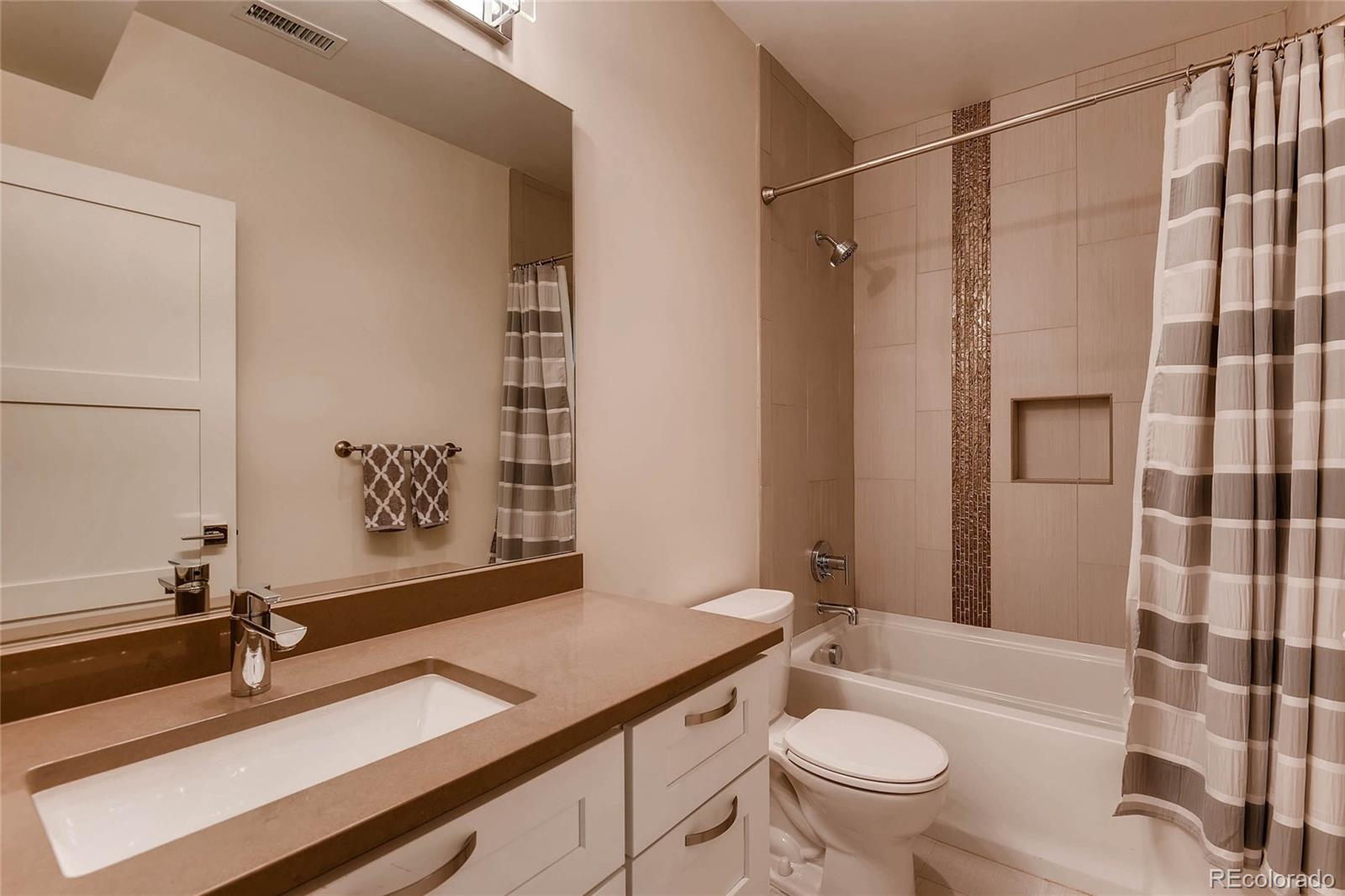 3957 Utica Street Denver, CO 80212 - Photo 22 of 28 a bathroom with a granite countertop sink toilet a mirror and shower