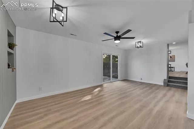an empty room with wooden floor and ceiling fan