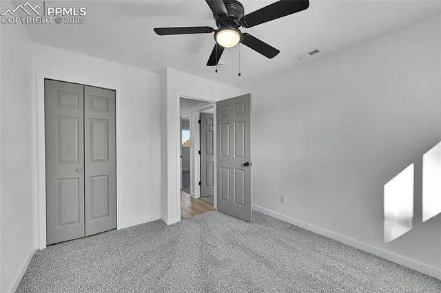an empty room with closet and a chandelier fan
