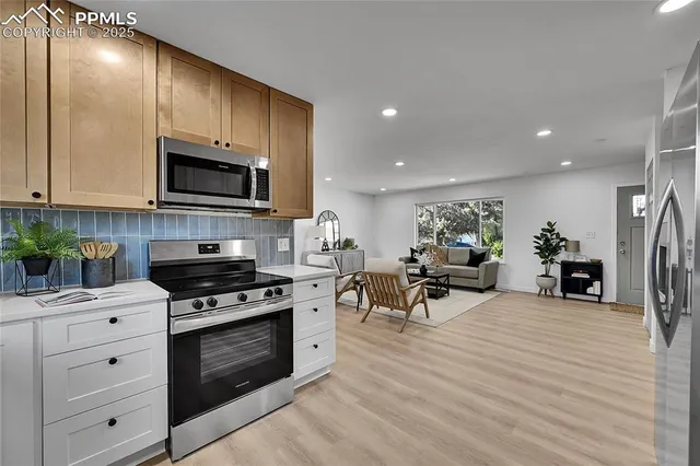 a living room with furniture a fireplace a flat screen tv and kitchen view