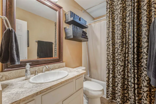 a bathroom with a granite countertop sink toilet and mirror