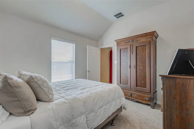 a bedroom with a bed and a dresser next to a window