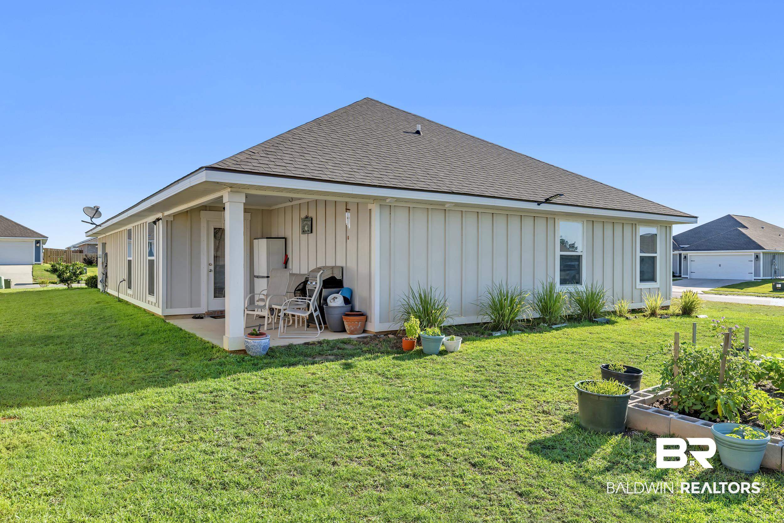 1228 Caper Avenue Foley, AL 36535 - Photo 30 of 54 Rear exterior featuring board and batten siding, a covered patio, and a shingled roof
