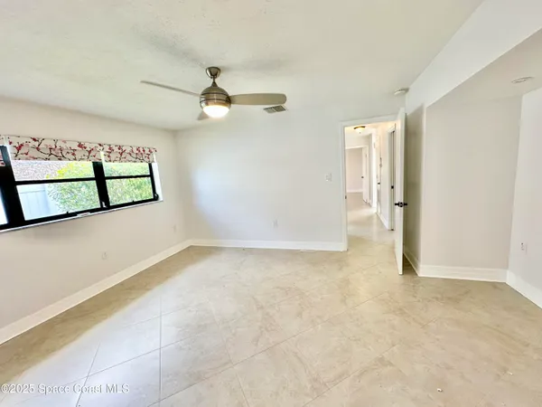an empty room with a chandelier fan and windows