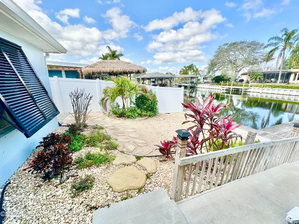 a view of a patio with a table and chairs under an umbrella with large trees