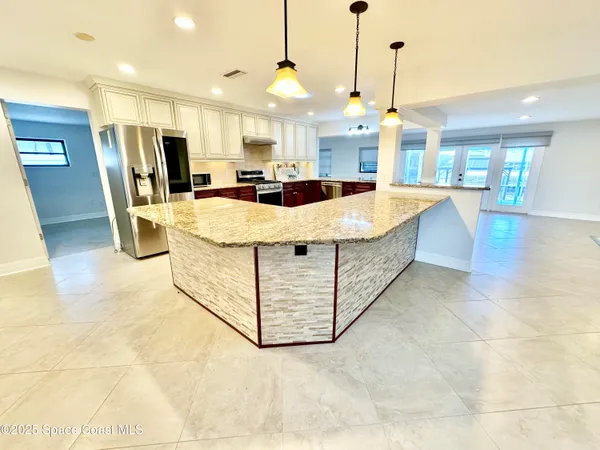 a large white kitchen with a large counter top appliances and cabinets