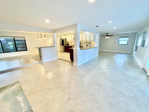 a view of an empty room with a window and a kitchen