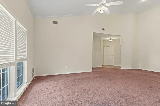 a view of an empty room with a chandelier fan