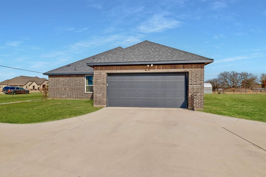 129 Altom Road Springtown, TX 76082 - Photo 3 of 40 a front view of a house with a yard and garage