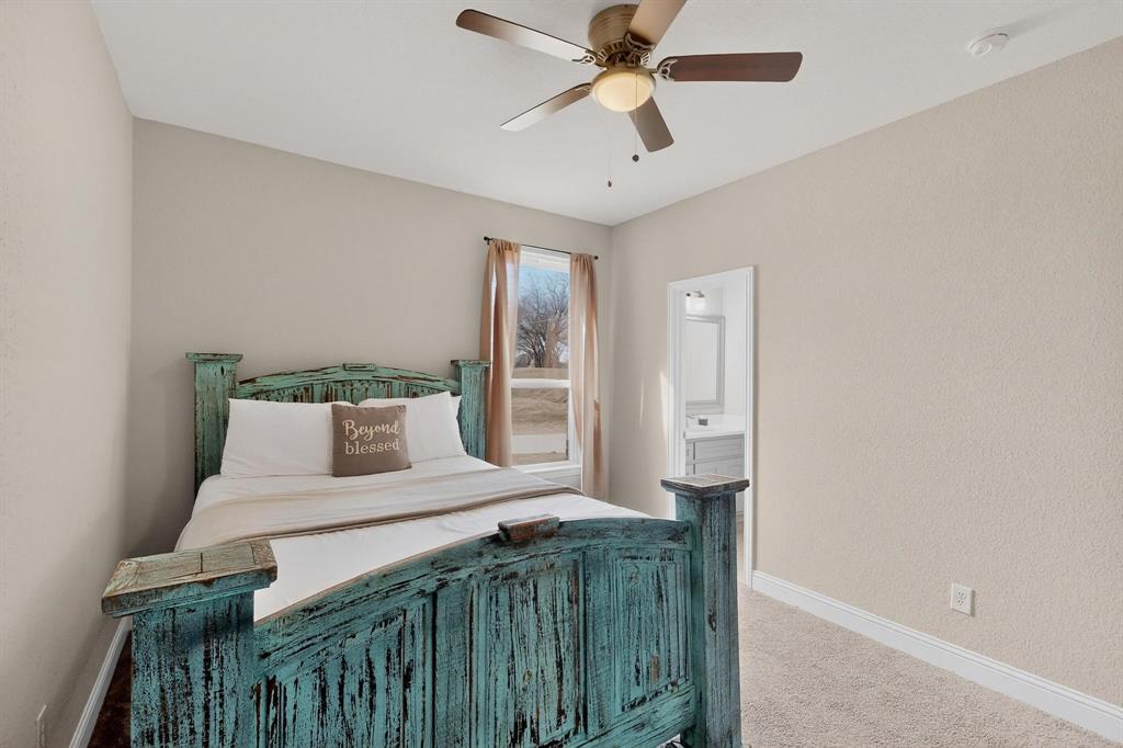 129 Altom Road Springtown, TX 76082 - Photo 35 of 40 a bedroom with a large bed and a chandelier