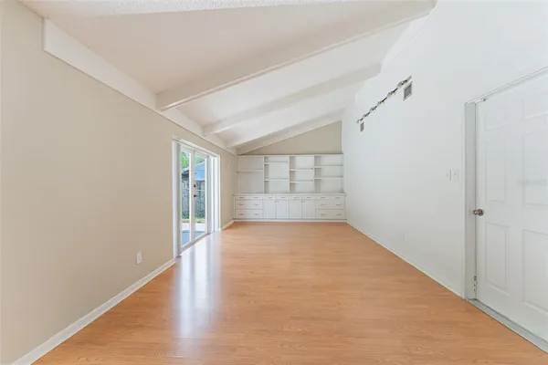 a view of an empty room with wooden floor and a window