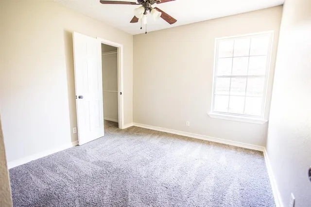 an empty room with a window and a ceiling fan