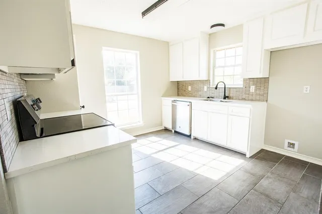 a kitchen with stainless steel appliances a sink a stove and white cabinets