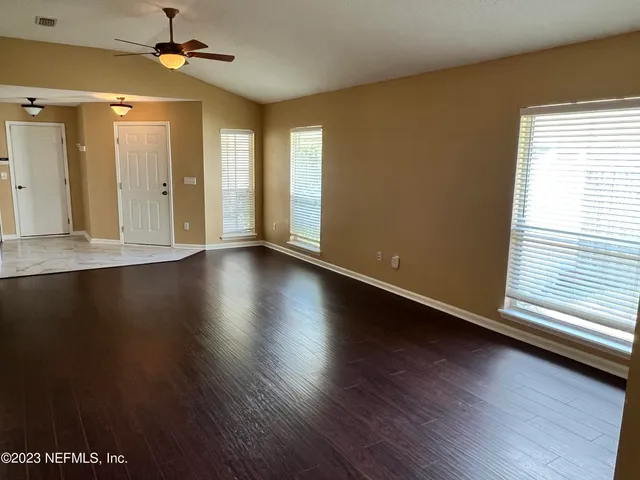 an empty room with wooden floor and windows