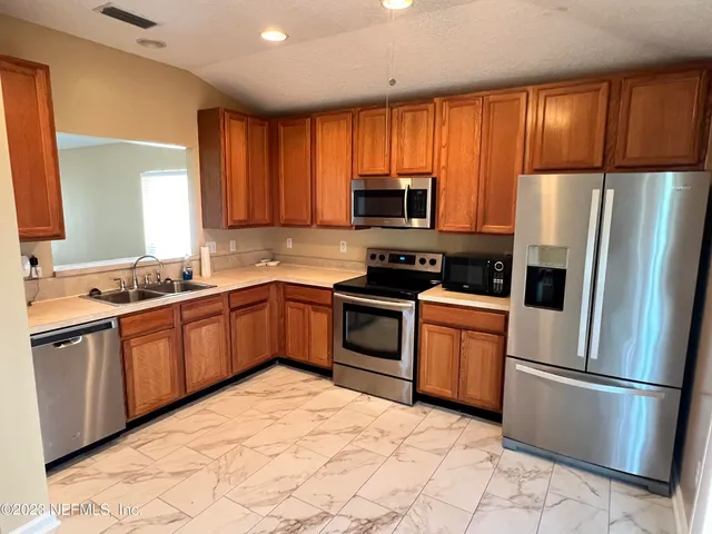 a kitchen with granite countertop stainless steel appliances a refrigerator sink and microwave