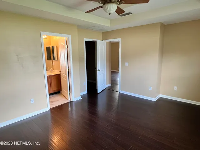 a view of an empty room with wooden floor and a ceiling fan