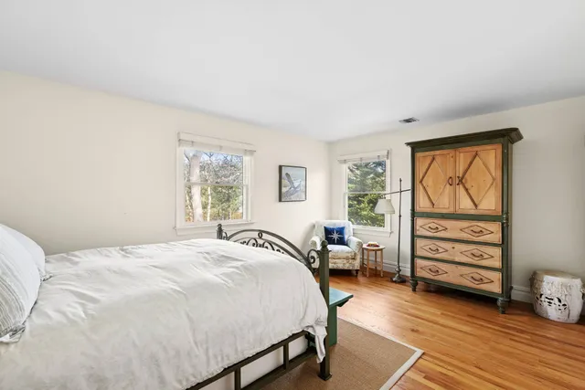 a bedroom with a bed a dresser and next to a window