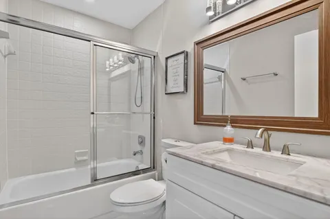 a bathroom with a granite countertop sink toilet and shower