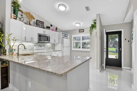 a kitchen with kitchen island granite countertop a sink a counter top space appliances and cabinets