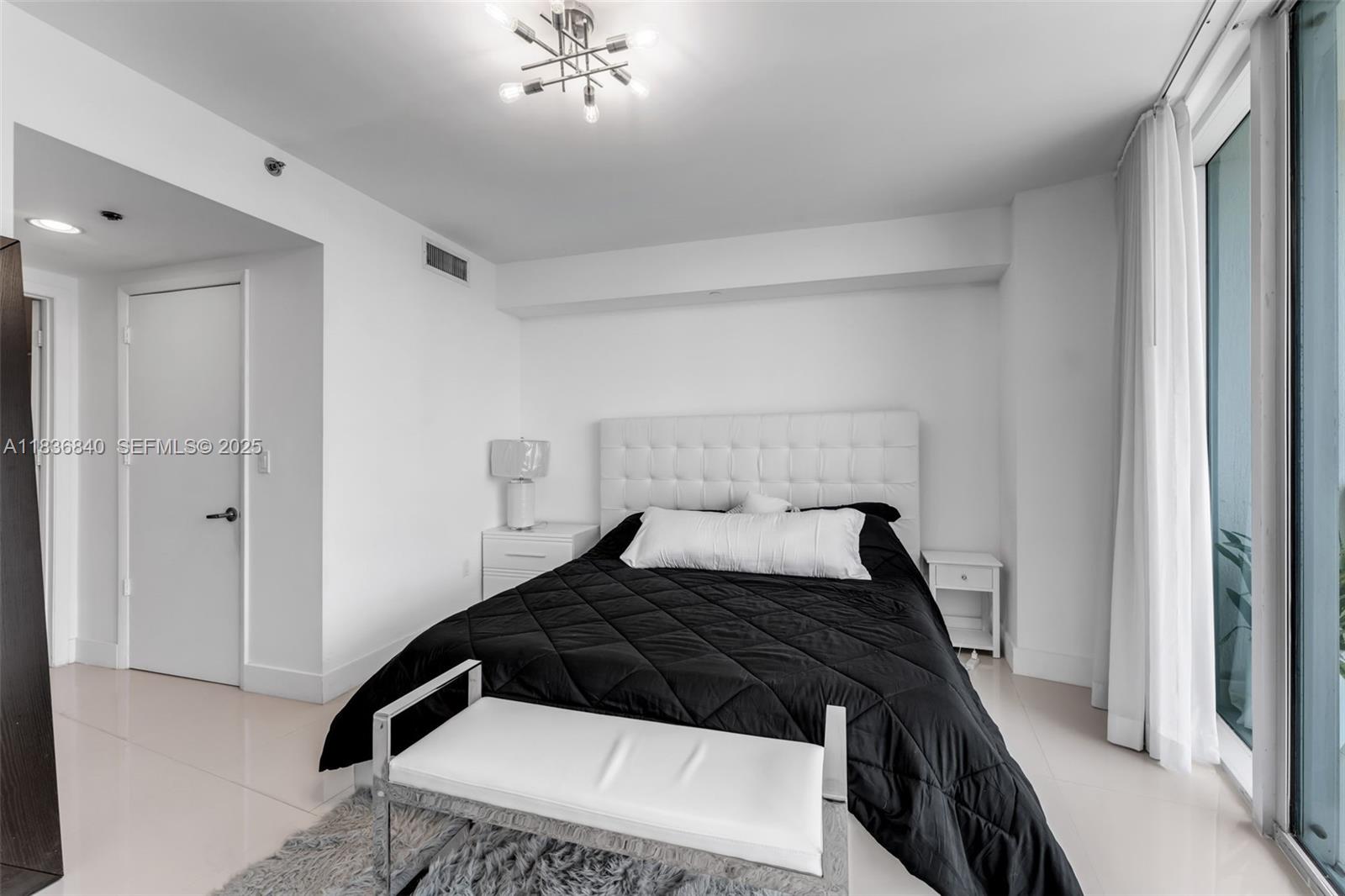 495 Brickell Avenue, Unit BAY1007 Miami, FL 33131 - Photo 10 of 34 a bedroom with a bed and a chandelier