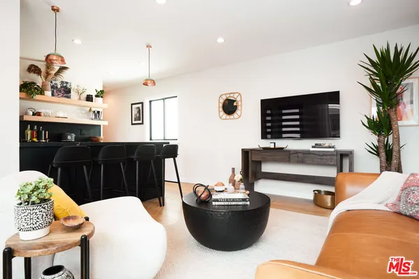 a living room with furniture kitchen view and a potted plant