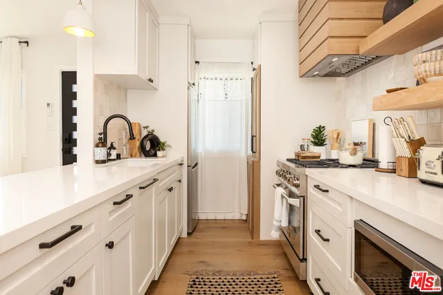 a kitchen with stainless steel appliances a sink stove refrigerator and cabinets