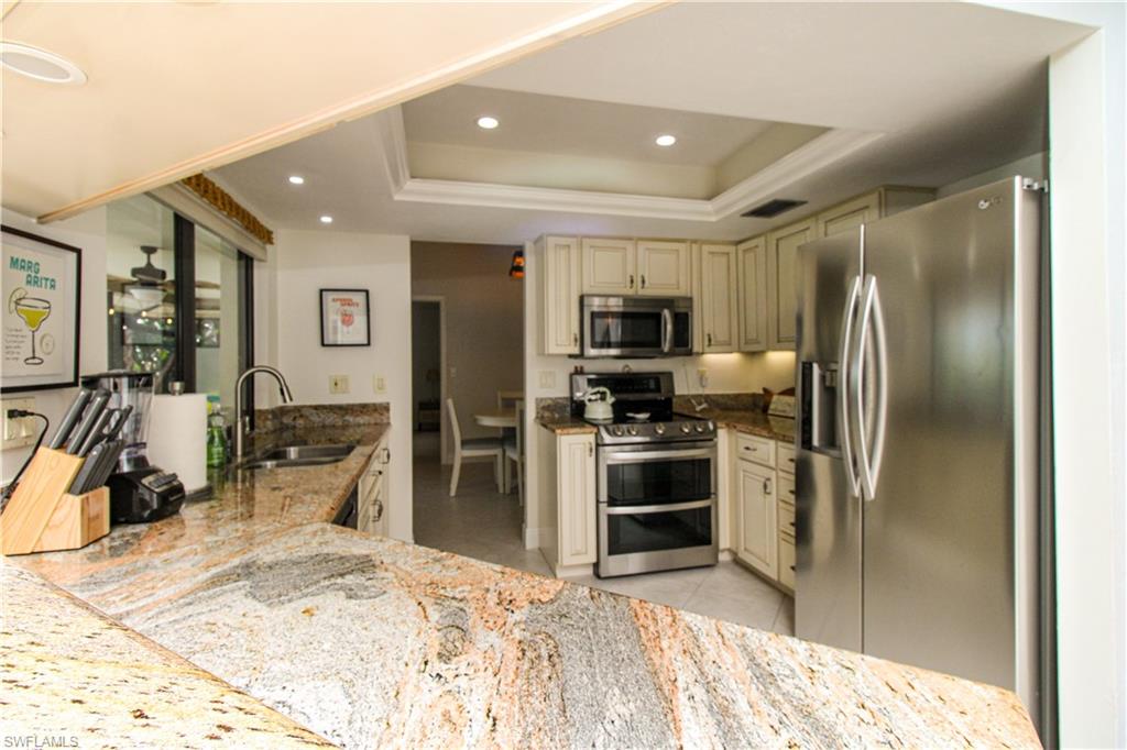 213 Bay Meadows Drive Naples, FL 34113 - Photo 21 of 50 a kitchen with stainless steel appliances kitchen island granite countertop a refrigerator and a sink