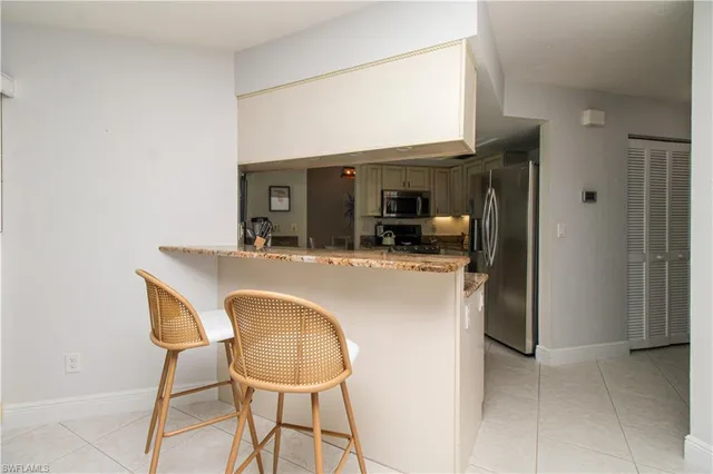a dining room with kitchen island stainless steel appliances a sink and a refrigerator