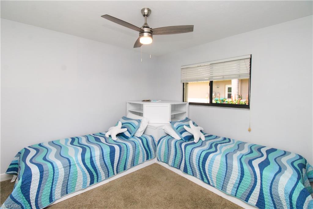 213 Bay Meadows Drive Naples, FL 34113 - Photo 38 of 50 a bedroom with two beds and a chandelier