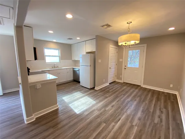a kitchen with refrigerator and wooden floor