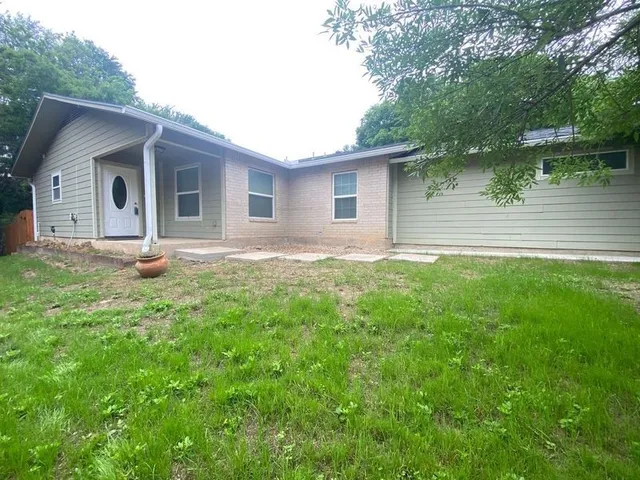 a backyard of a house with plants and large tree