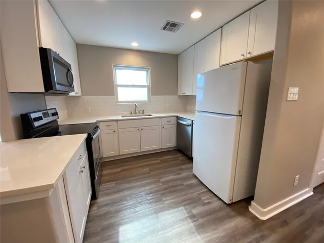 a kitchen with a refrigerator a stove a microwave and wooden floor