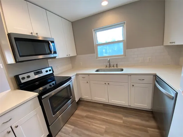 a kitchen with white cabinets appliances and a sink
