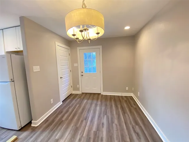 an empty room with wooden floor and a hallway
