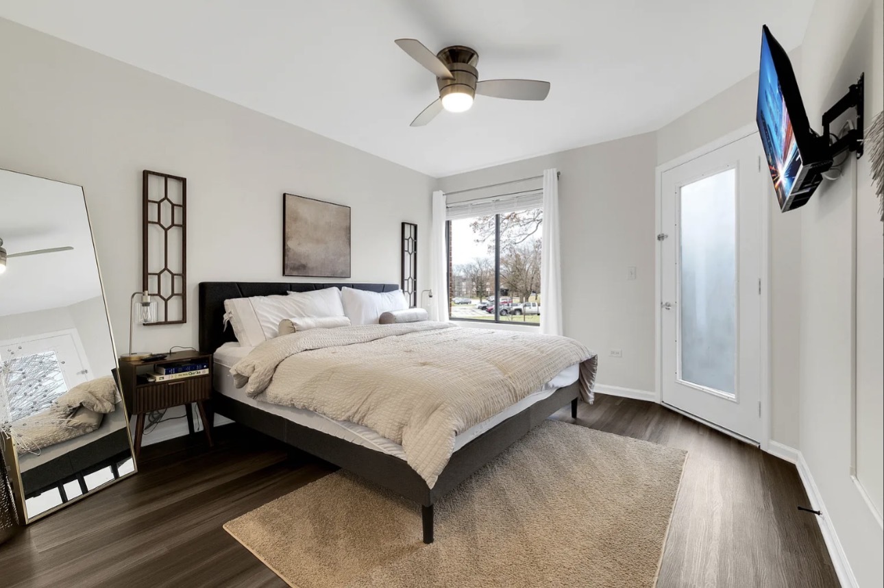 379 Sandhurst Circle, Unit 1 Glen Ellyn, IL 60137 - Photo 13 of 20 a spacious bedroom with a bed a couch and a chandelier