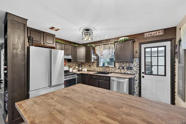 a kitchen with granite countertop a refrigerator stove top oven and sink