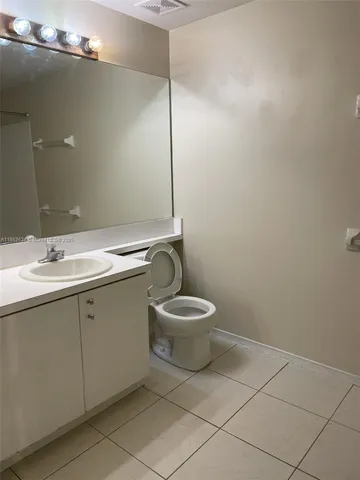 a bathroom with a granite countertop toilet a sink and a mirror