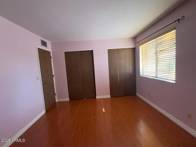 a view of an empty room with closet and a window